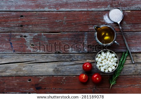 Top view of tomatoes, mozzarella cheese and olive oil on rustic wooden background. Lots of copy space. Vegetarian food, health or cooking concept.