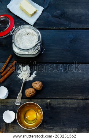 Butter, flour in glass jar, eggs for baking over rustic wooden board from above. Ingredients background with space for text. Cooking concept.