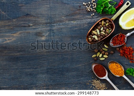 Various spices in old metal scoop and spoons, herbs and spices over dark wooden background with space for text. Cooking ingredients.