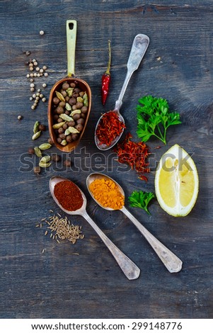 Top view of spices in old metal scoop and spoons, herbs and spices over dark wooden background. Cooking ingredients.