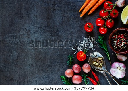 Spices, herbs and fresh vegetables for cooking on dark metal background with space for text. Top view. Bio Healthy food ingredients.