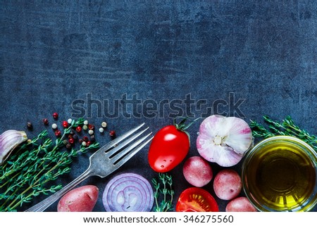 Fresh herbs, organic vegetables, olive oil and spices for cooking on dark vintage background. Healthy food. Vegetarian eating. Top view. Dark rustic background layout with free text space