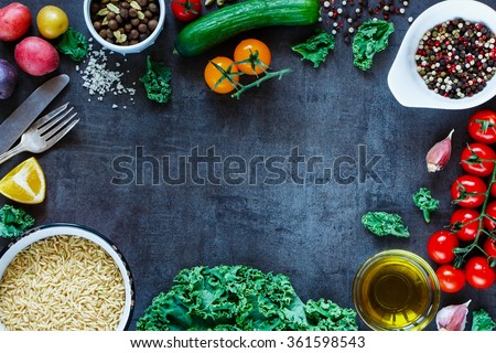 Brown rice with fresh delicious vegetables and ingredients for tasty cooking on vintage dark background. Top view. Diet or Sports nutrition concept.