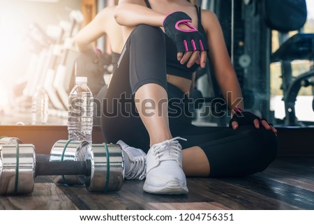 woman in black fitness suite sitting and breaking relax while exercise workout in gym