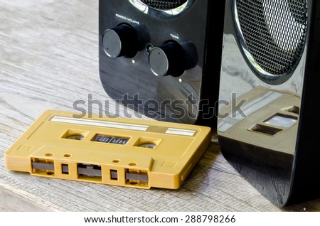 Old tape cassette and speaker on wooden table.
