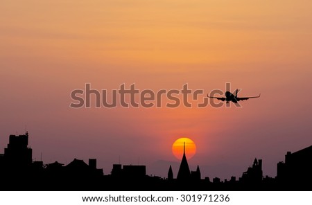 Big city silhouette and airplane against the sky on a sunset
