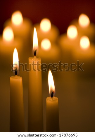 Three candles with glowing candles in background