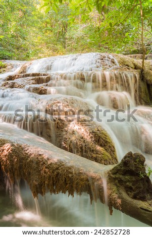 A stream flowing through foggy Autumn woodland at Erawan falls in Thailand National park