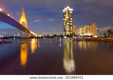 Abstract blurred bokeh light of bridge and residence building  with water reflection