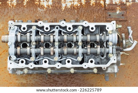 cylinder head and bent shaft on the background of rusty metal, broken engine car parts