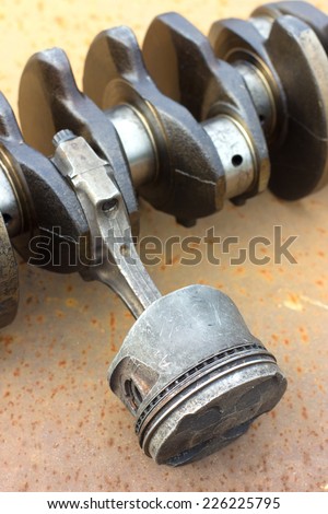 worn piston to the connecting rod and crankshaft lying on a rusty metal. car parts
