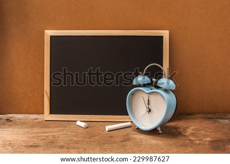 blank blackboard for fill text with old retro clock on wooden background , vintage color tone. abstract back ground to time for write some thing.