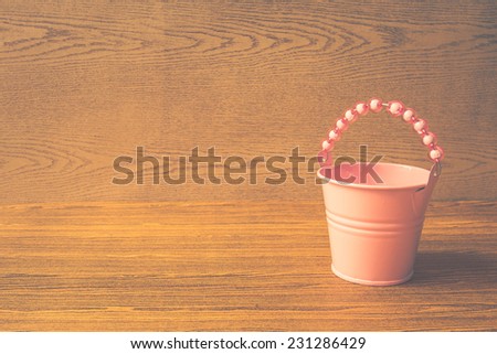 sweet pink bucket on wooden background. vintage color tone