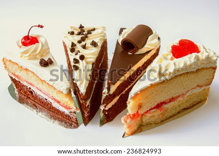 four piece of chocolate layer cake with chocolate ship topping cream and vanilla layer cake with cherry currant cream on gray background.