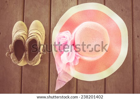 pink beach hat and vintage shoes on wooden background. vintage color tone.