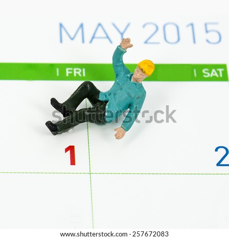 miniature worker sitting on calendar of 1 May, abstract background for celebrate happy labor day.