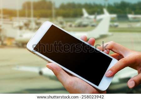 woman hand hold and touch screen smart phone,tablet,cellphone in the airport terminal