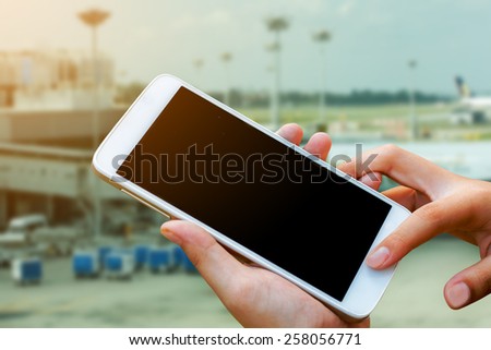 woman hand hold and touch screen smart phone,tablet,cellphone in cargo of  airport terminal