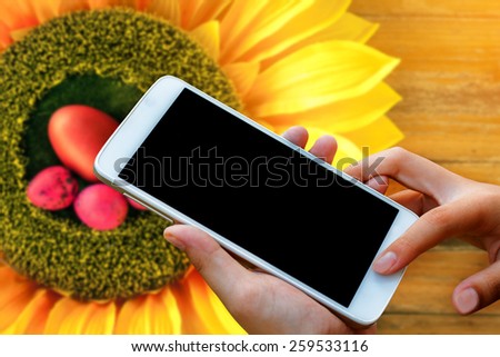 woman hand hold and touch screen smart phone, tablet,cellphone on blurred beautiful easter holiday decorate.