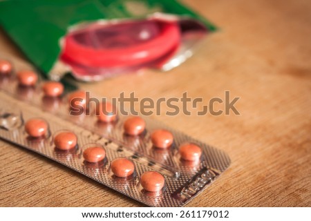 birth control pills and condom on wooden table background.soft and selective focus.