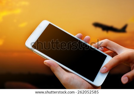 woman hand hold and touch screen smart phone,tablet,cellphone in the airport terminal on sunset.