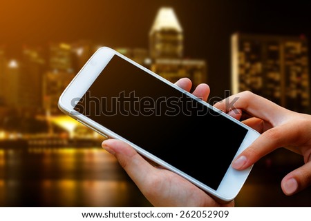 woman hand hold and touch screen smart phone, tablet,cellphone over city night light background.