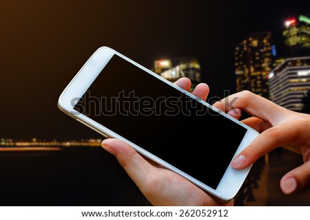 woman hand hold and touch screen smart phone, tablet,cellphone over city night light background.