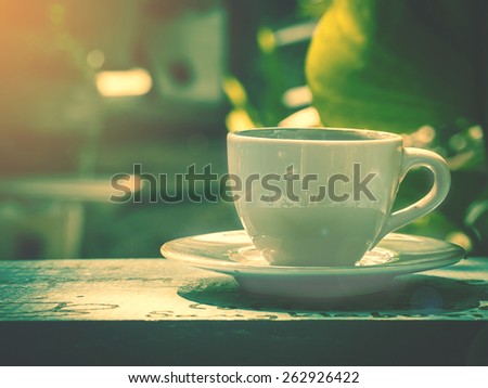 white cup of coffee or tea  in garden with sun lighting.