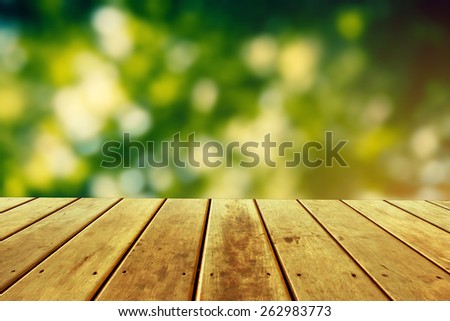 fresh spring green garden with green bokeh and sunlight over wood floor. beauty natural background