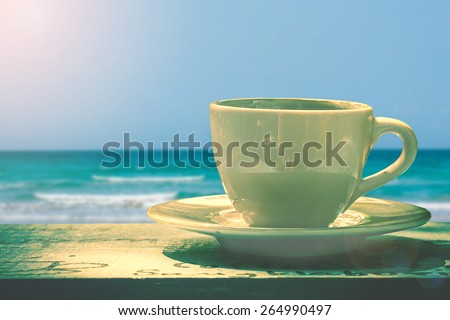 cup of coffee on wooden background over blue sky and sea on day noon light.