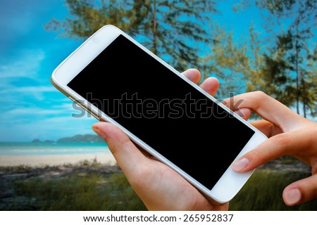 woman hand hold and touch screen smart phone, tablet,cellphone on blurred beautiful beach background.
