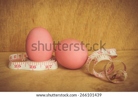 eggs and measure tape on wooden background,abstract background to good food foe diet concept.