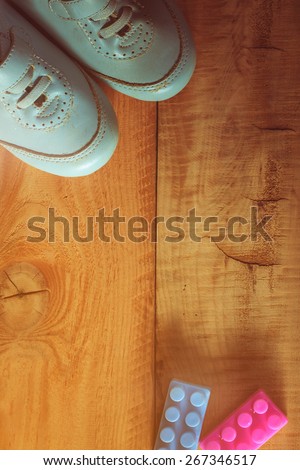 top view of old boy shoes on wooden floor with plastic toy,abstract background to first step concept.vintage color photo.
