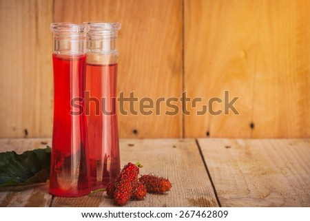 bottle of mulberry fragrance oil,essential oil with mulberry fruit on wooden floor.