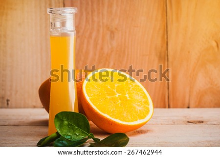 bottle of orange fragrance oil,essential oil with orange cut on wooden floor.