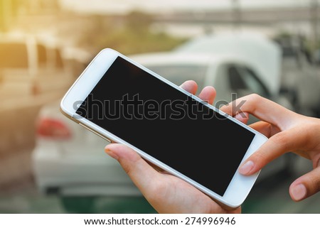 woman hand hold and touch screen smart phone, tablet,cellphone on city traffic accident  in morning background.