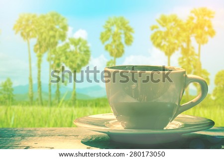 white cup of coffee or tea over palm tree and blue sky.