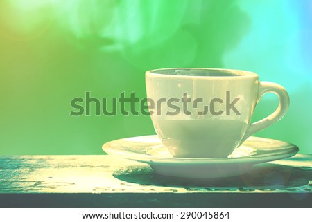 white cup of coffee or tea on wooden table in garden with sun lighting.