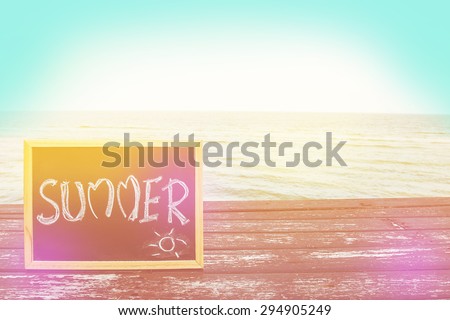 love summer decorate with heart and chalkboard on wooden floor on the blue sea with filter colored.