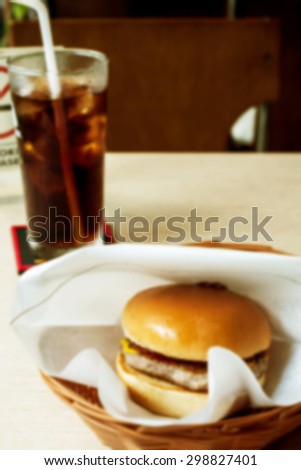 blurred hamburger and cola on restaurant table on day noon light abstract background for junk food concept.