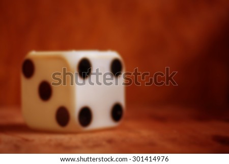 blurred of one old dice on wooden table,vintage color tone,abstract background to risk management concept.