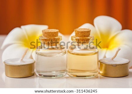 bottle of aroma essential oil with flower and candle on wooden background, spa concept.