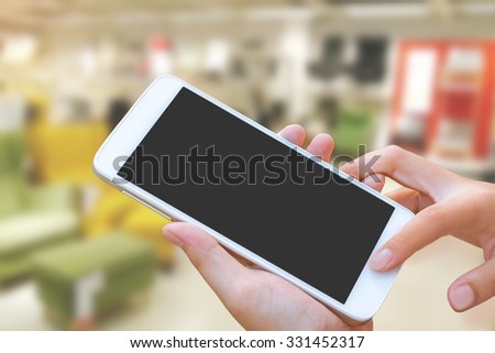 woman hand hold and touch screen smart phone, tablet,cellphone over furniture and home for sale background, abstract background for solution of house or home or property.