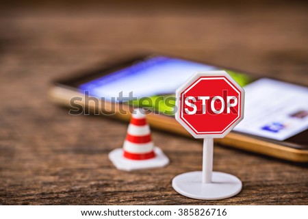 stop sign with traffic cone over blurred smart phone, tablet,cellphone on wooden floor,abstract background to safety drive don\'t use smartphone,cellphone or tablet concept.