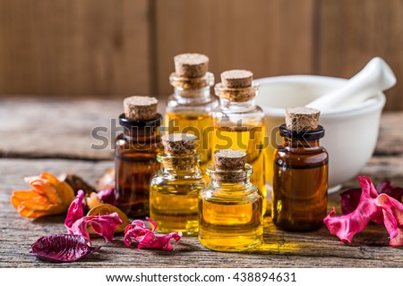 bottle of aroma essential oil with dry flower and mortar on wooden table, spa concept.