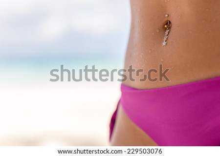 Young girl\'s slim belly with the beach on background