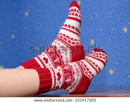 feet with christmas socks on the table at home on blue background