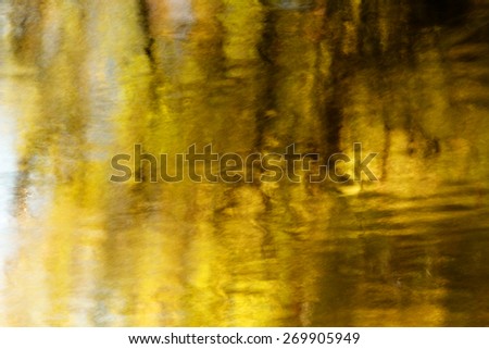 Timed exposure of fall leaves reflecting win a moving river giving a blurred abstraction of the fall colors.