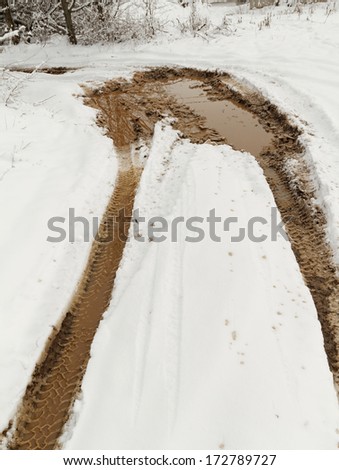 Traces from wheels of the car on muddy snow