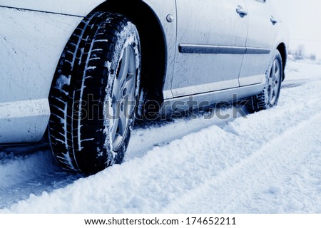 Close up of a cars tires on a snowy road - blue tone